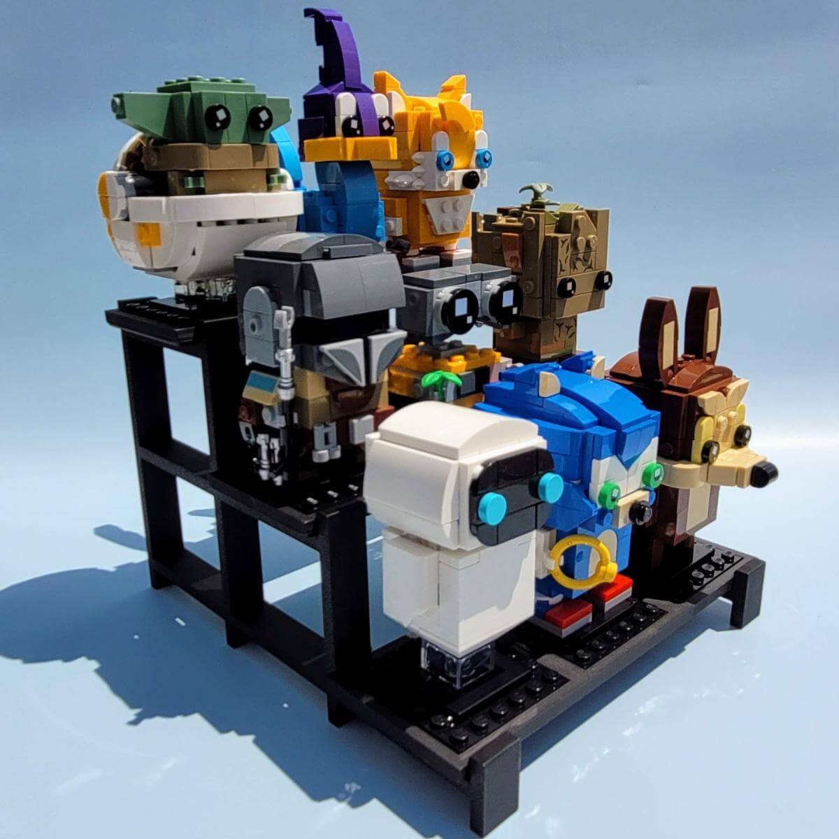 Side angle view of a black display stand holding nine LEGO BrickHeadz, showing the tiered structure and strong support. Each figure is raised for maximum visibility, creating a clean and organized presentation. Great for collectors looking for a compact, efficient way to show off BrickHeadz on a shelf or desk. Figures not included.