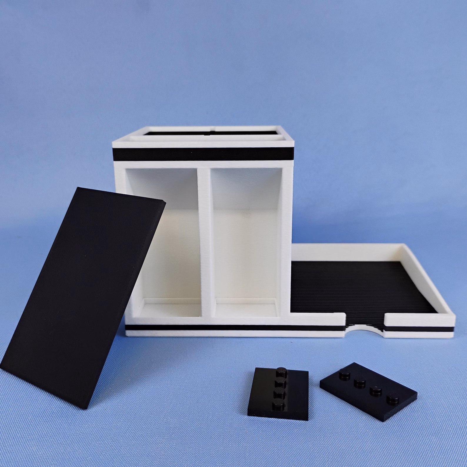 Post-it note holder desk organizer shown with modular components separated. Displays the sticky note tray, pen holder, and removable parts to illustrate how the organizer is assembled.
